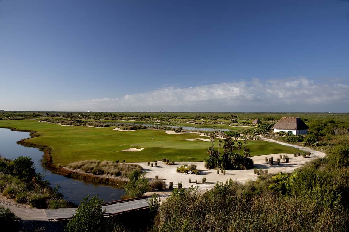 un campo de golf con un río y un edificio