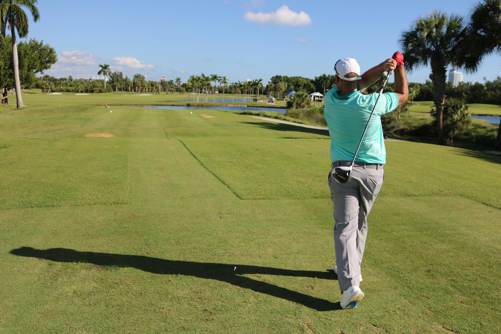 Un hombre balanceando un palo de golf en un campo de golf